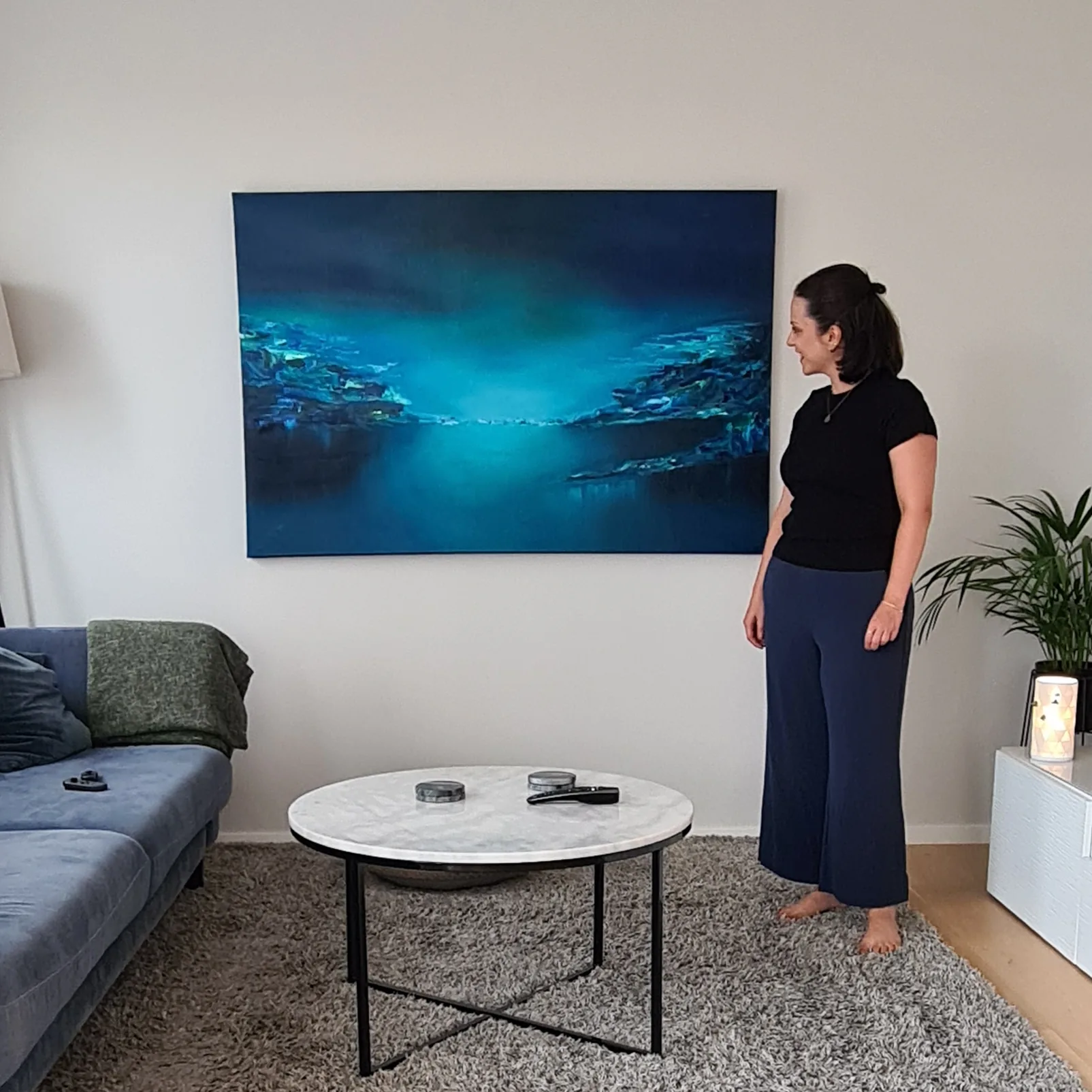 Sedef Ünlü standing beside one of her large blue paintings