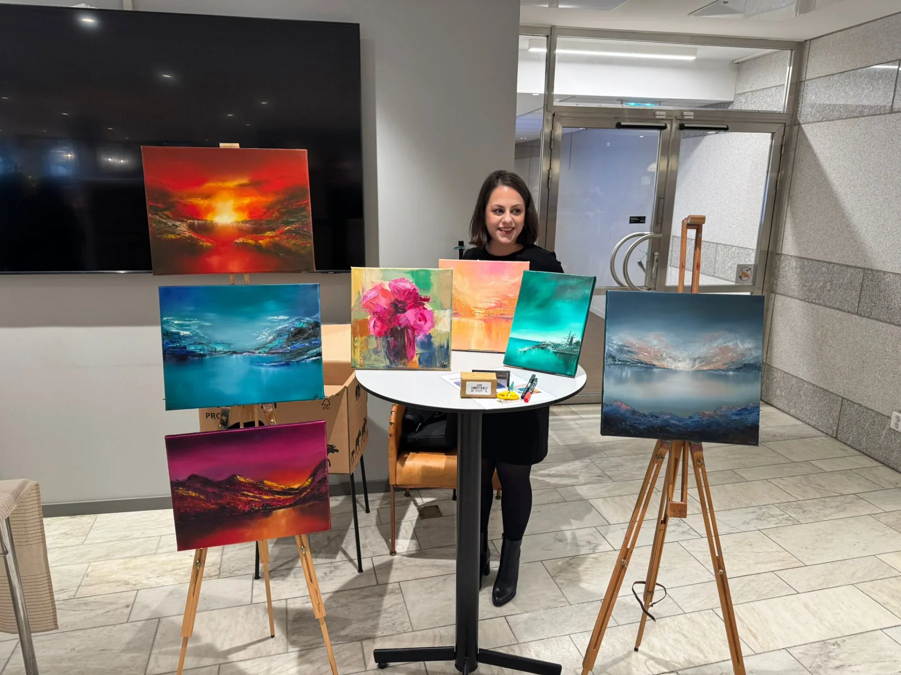 Sedef Ünlü with a group of her paintings on easels at a showing in Stockholm